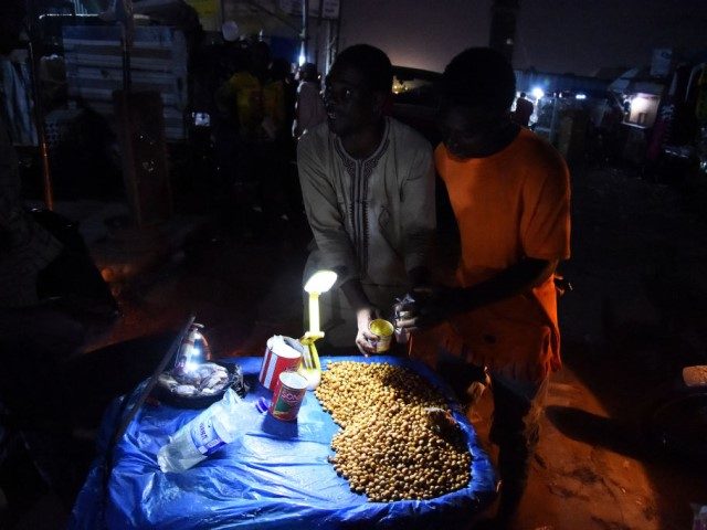 A roadside vendor sells Tigernuts lit up with torchlight at a market without electricity a