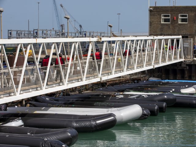 Asylum seekers walking up the gangway after being rescued in the English Channel passed al