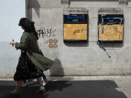 Two women pass by Barclays cash points, both boarded up and vandalised by graffiti, as a leading think tank predicts that surging rates of inflation and weak economic growth in the country could contribute towards a recession, with many households slipping into poverty on 10th May, 2022 in Leeds, United …