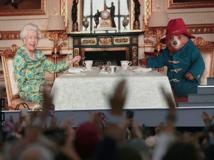 The crowd watching a film of Queen Elizabeth II having tea with Paddington Bear on a big s