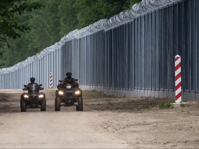 Border guards patrol on quads along the border wall at the Polish-Belarusian border near T