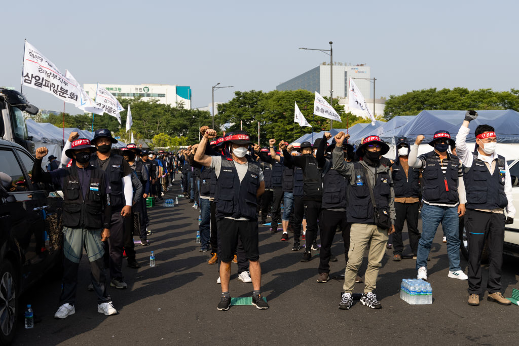 Truck drivers and members of the Korean Confederation of Trade Unions shout slogans during a demonstration in front of the Uiwang Inland Container Depot in Uiwang, South Korea, on Friday, June 10, 2022. Thousands of truck drivers who are seeking to prevent a change to wage rules have gone on strike at major ports and container depots, posing the latest threat to strained global-supply chains. Photographer: SeongJoon Cho/Bloomberg via Getty Images