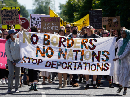 Protesters hold up placards as they march towards the Brook House immigration removal centre beside Gatwick Airport, south of London on June 12, 2022, to demonstrate against the UK government's intention to deport asylum-seekers to Rwanda. - UK campaigners get their last chance in court on Monday to stop the …