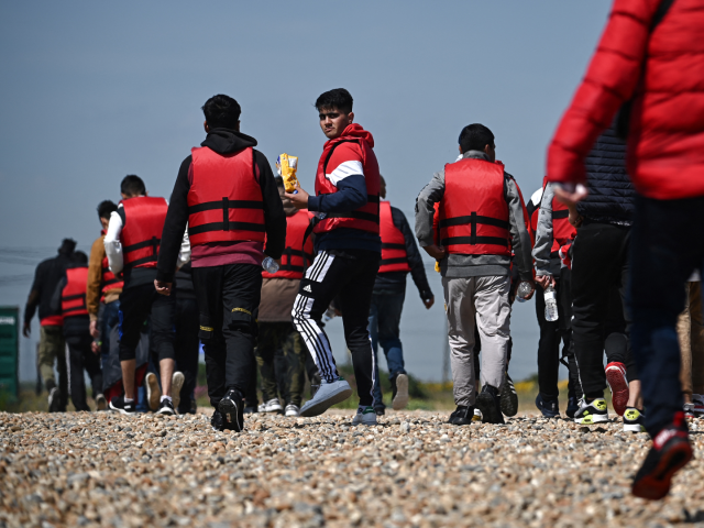 Migrants walk up the beach in Dungeness, on the southeast coast of England, on June 15, 20