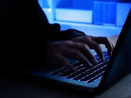 A computer programmer or hacker prints a code on a laptop keyboard to break into a secret