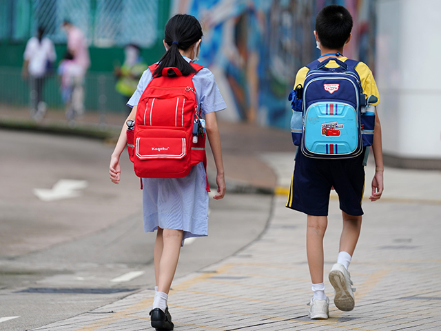 Students wearing face masks walk to school on the first day of the reopening amid the coro