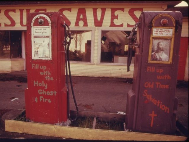 Color photograph of an abandoned gas station being used as a billboard for religious messa