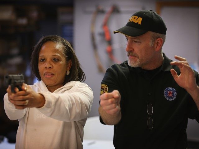 TINLEY PARK, IL - JANUARY 19: NRA certified firearms instructor Craig Marshall (R) teaches Cheryl Bourgeois how to fire a pistol during an NRA Basic Pistol Course at Freddie Bear Sports sporting goods store on January 19, 2012, in Tinley Park, Illinois. Gun rights supporters have proclaimed today Gun Appreciation …