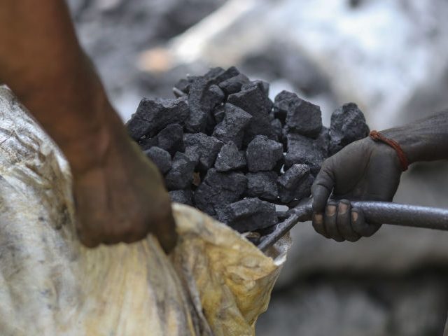 Workers load coal into a sack at a coal wholesale market in Mumbai, India, on Thursday, Ma