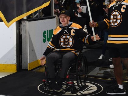 BOSTON, MA - MAY 12: Fan banner captains Jake Thibeault, Milton Academy hockey player who suffered a spinal chord injury that left him paralyzed form the waist down, and New England Patriots running back Damien Harris #37 before the game of the Boston Bruins against the Carolina Hurricanes in Game …