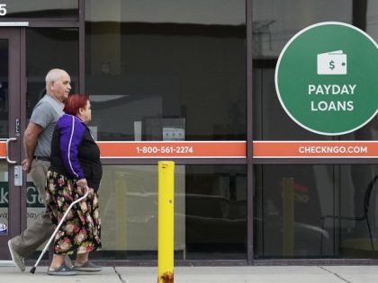 Pedestrians walk past a "Payday Loans" sign displayed at a Check'n Go in Niles, Ill., Sunday, July 11, 2021. (Nam Y. Huh/AP)