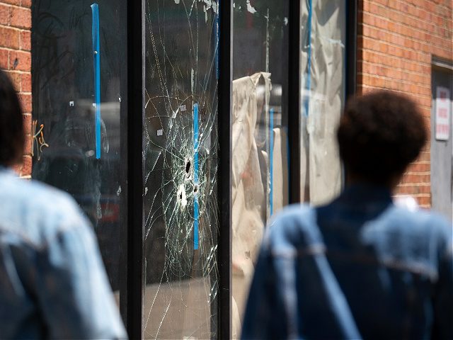 Pedestrians walk past bullet holes in the window of a store front on South Street in Philadelphia, Pennsylvania, on June 5, 2022. (Photo by Kriston Jae Bethel / AFP) / The erroneous mention[s] appearing in the metadata of this photo by Kriston Jae Bethel has been modified in AFP systems …