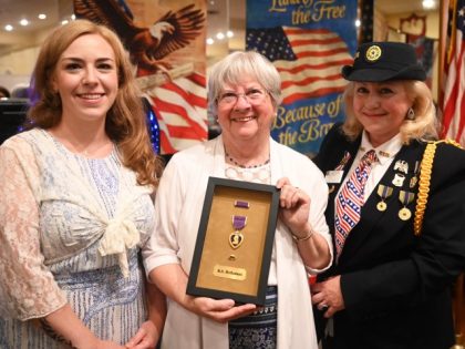 At a ceremony at Polish Hall in Riverhead, New York, on June 26, 2002, Lynn Holloman Bryson, 71, of Seattle (center), holds the Purple Heart that her late father Robert had received for his service during World War ll. At left is Kristen Asher- O'Rourke, who had tracked down Bryson …