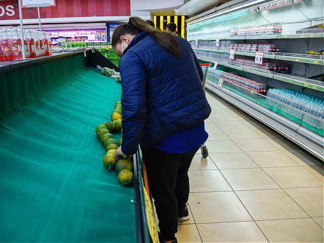 A customer looks at a supermarket shelf with shortage of fruits and vegetables, in Quito o