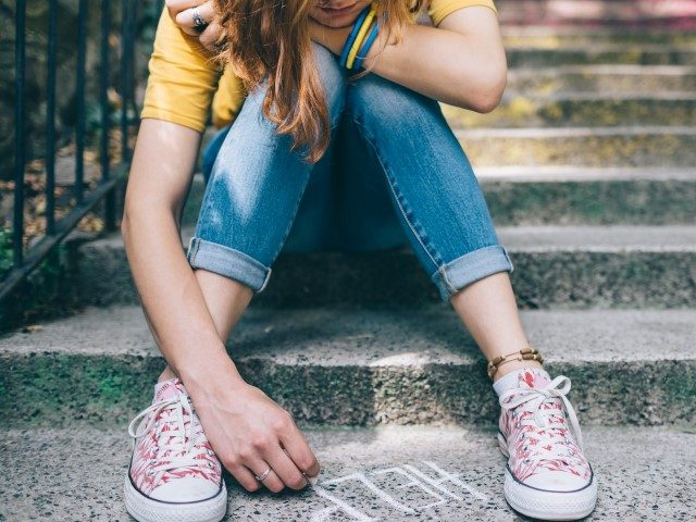 Sad teenage girl writes 'help' (Getty)