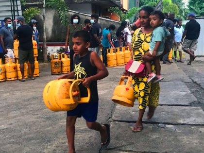 A mother and her child carry liquefied petroleum gas (LPG) cylinders in Colombo on June 11