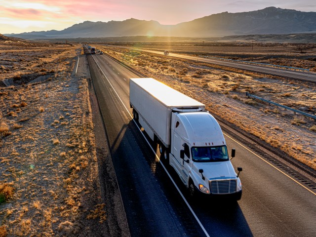 A semi-trailer truck heads down a four-lane highway at dusk delivering a load in the southeastern Utah desert on Interstate 70 east bound. (Getty)