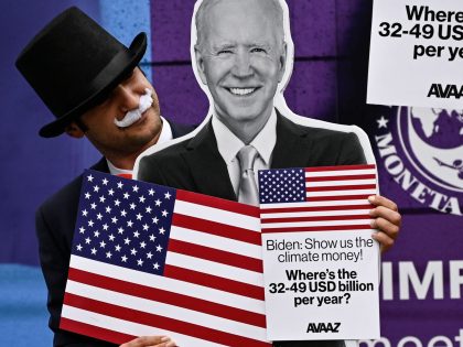 An activist dressed as debt collectors" holds a cutout of US President joe Biden during a demostration in front of the International Monetary Fund headquarters to ask rich nations to keep their comitment to support developing countries to tackle climate change in Washinton DC on October 13, 2021. - The …