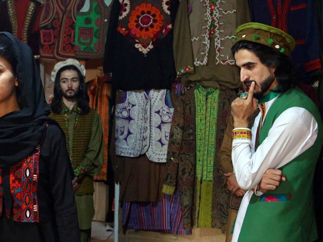 FILE - Ajmal Haqiqi, right, watches as Mahal Wak, center, practices modeling, in Kabul, Af