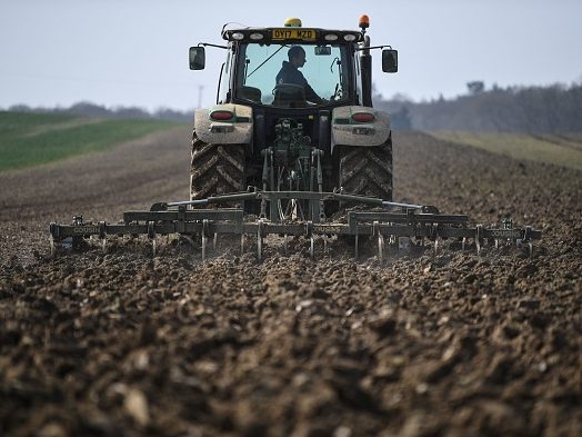 A tractor cultivates the ground for rapeseed oil crops at the Westons Farm, in Itchingfiel