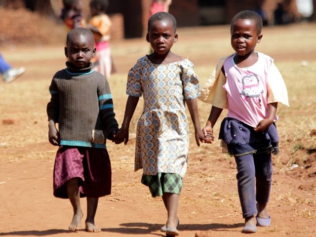 Three small girls are seen holding hands as they head home from a function at a community