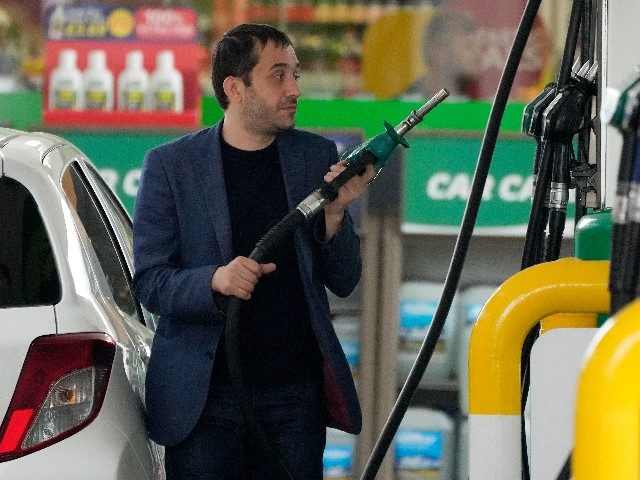 A driver looks at the petrol pump after picking up a nozzle to fill up his car with fuel i