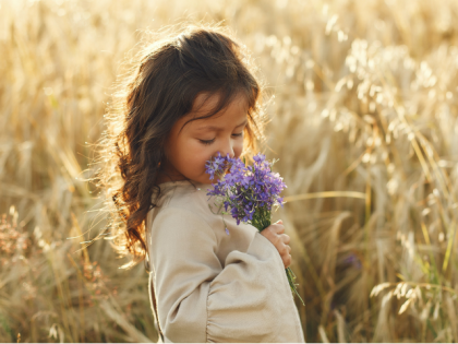 Little Girl on a Wheat Field Smelling Flowers in Her Hand