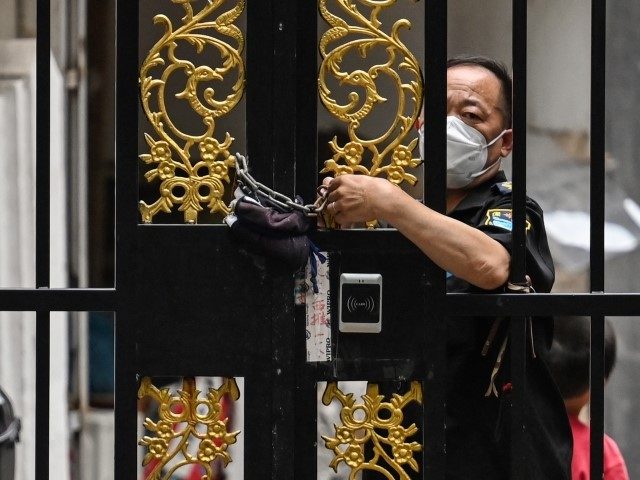 A security worker locks a door with a chain in a neighbourhood under a Covid-19 lockdown i