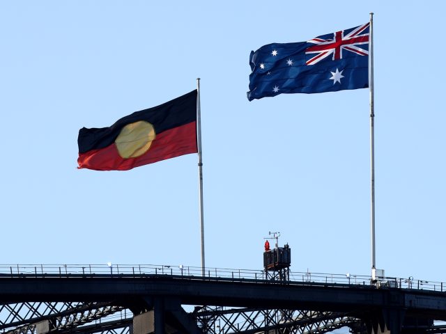 SYDNEY, AUSTRALIA - JANUARY 26: The Aboriginal flag flies alongside the Australian flag on top of the Harbour Bridge during the Australia Day Live concert at Sydney Opera House on January 26, 2022 in Sydney, Australia. (Photo by Don Arnold/WireImage)