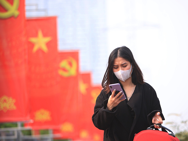 In this Jan. 23, 2021 file photo, a woman wearing face mask looks at her phone in Hanoi, V