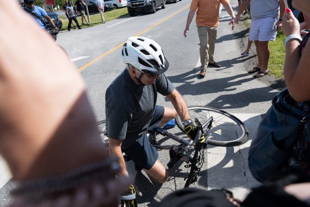 US President Joe Biden falls off his bicycle while approaching well-wishers during a bike