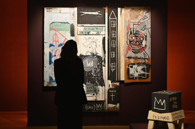 A woman looks at Jean-Michel Basquiat's 'Portrait of the Artist as a Young Derelict' durin