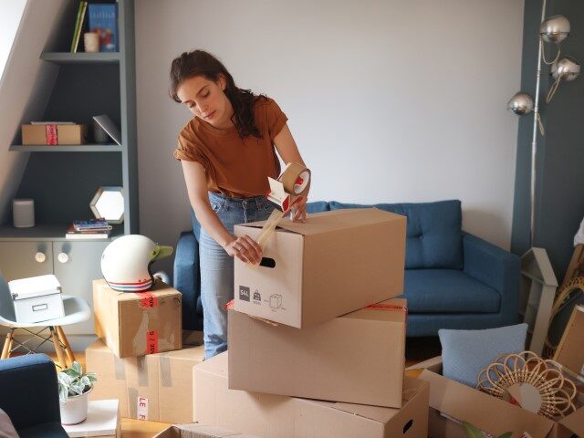 A young woman is packing her moving boxes