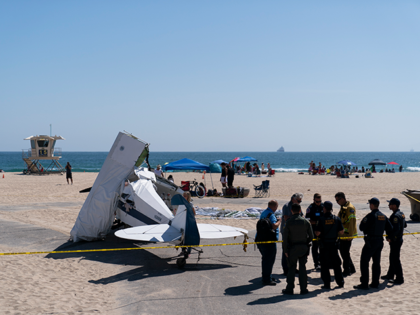 Investigators stand next to a small plane that was pulled from the water after it crashed into the ocean in Huntington Beach, Calif., Friday, July 22, 2022. The plane towing a banner crashed in the ocean Friday during a lifeguard competition that turned into a real-life rescue along the popular …