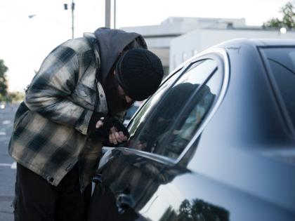 USA, Utah, Salt Lake City, Homeless man breaking into car, side view - stock photo