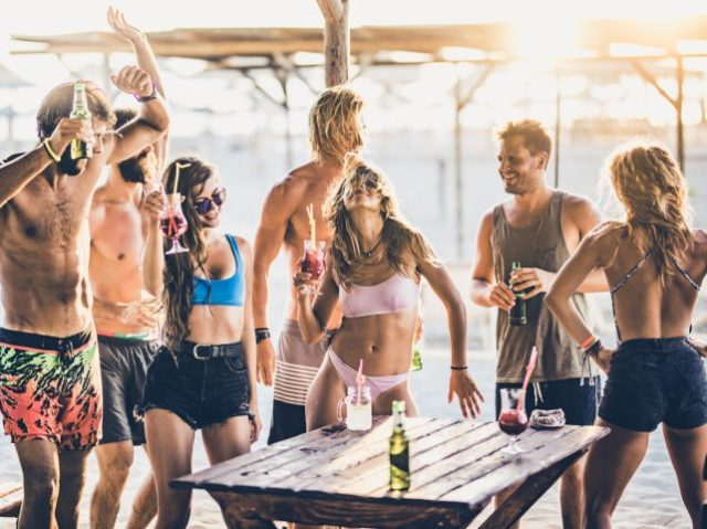 Large group of friends having fun while dancing on a party in a beach bar.
