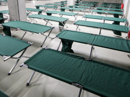 Camp folding cots are being set up in the underground parking of a stadium and wait for re