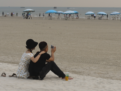 A couple seen on Silver Beach in Beihai during cloudy weather. Silver Beach, located 8km from downtown Beihai, stretches about 24km from east to west, and is regarded 'the greatest beach in China' because of the fine and white sand, soft waves, clean seawater and safe environment without sharks. On …