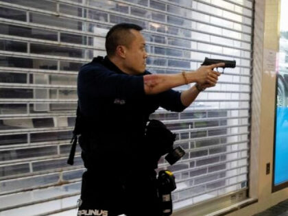 A police officer points a weapon during a protest in the Mong Kok district of Hong Kong, C