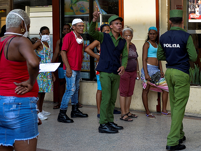 Policemen help organize people waiting in line to buy food in Havana on April 17, 2020, am