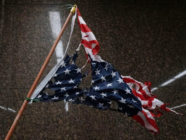 TOPSHOT - A torn and burnt upside down American flag hangs, as protesters march through th