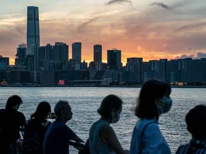 People wearing face masks enjoy a moment during sunset at the harbour front on July 16, 20