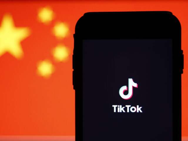 The TikTok logo is displayed on a smartphone in front of the national flag of China in thi