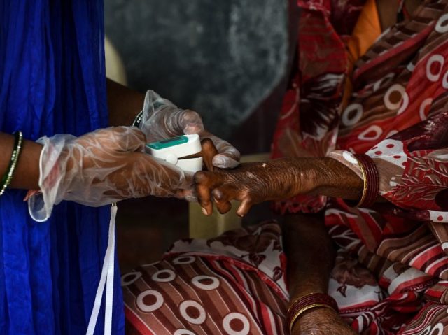 A 'Covid-19 Awareness Project' volunteer (L) uses an oximeter to check on a patient infected with leprosy as part of a general health checkup for all inmates at the Gandhi Leprosy Seva Sangh rehabilitation centre, in Ahmedabad on October 11, 2020. (Photo by SAM PANTHAKY / AFP) (Photo by SAM PANTHAKY/AFP via Getty Images)