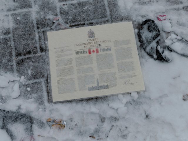 The laminated Charter of Rights and Freedoms is seen on the ground during the clean up of Wellington Street in front of Parliament Hill, previously occupied by the Freedom Convoy, in Ottawa, Ontario, Canada, on February 20, 2022. - The last big rigs were being towed Sunday out of Canada's …