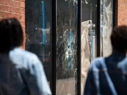Pedestrians walk past bullet holes in the window of a store front on South Street in Philadelphia, Pennsylvania, on June 5, 2022. (Photo by Kriston Jae Bethel / AFP) / The erroneous mention[s] appearing in the metadata of this photo by Kriston Jae Bethel has been modified in AFP systems …