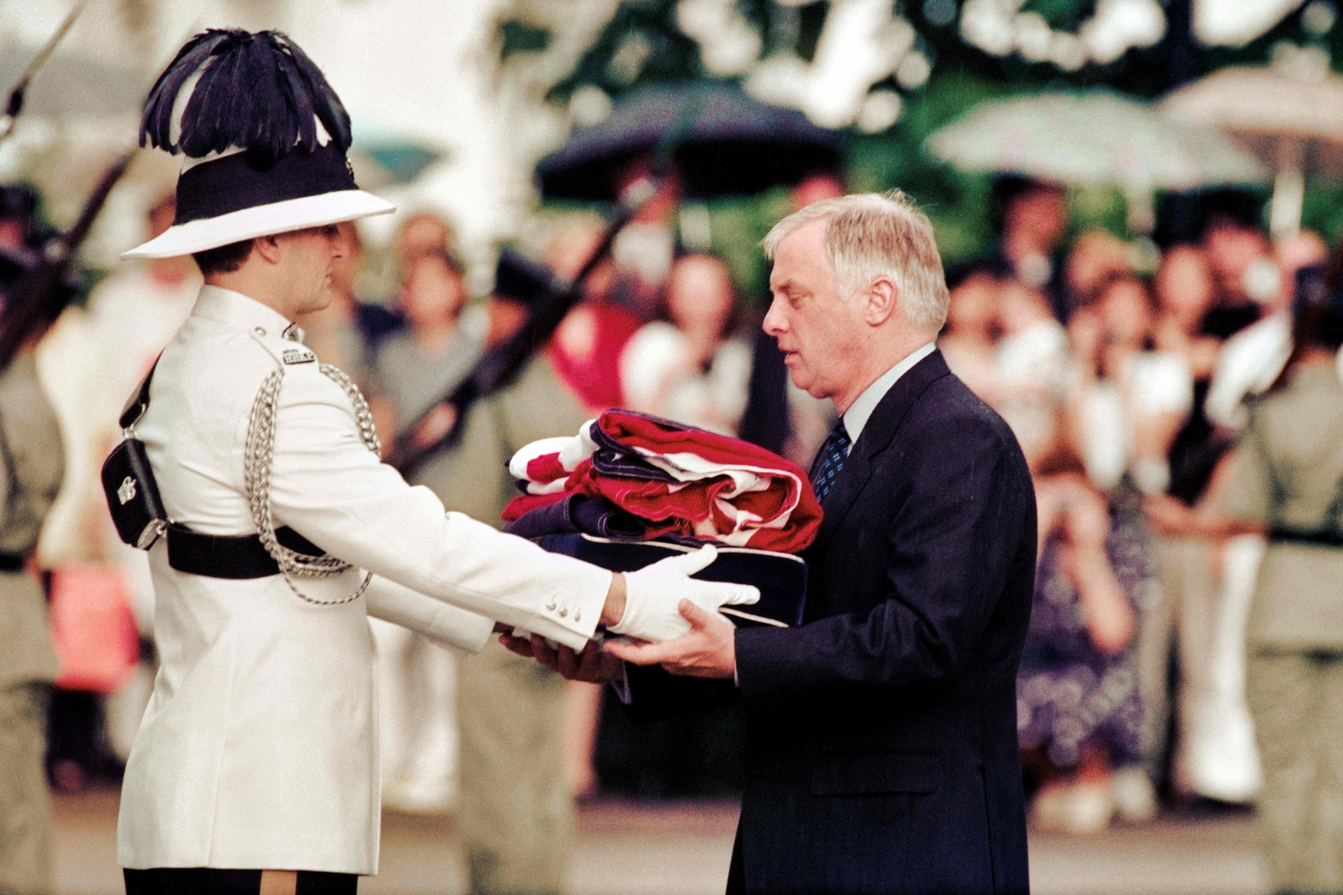 Chris Patten (R), the 28th and last governor of colonial Hong Kong, receives the Union Jack flag after it was lowered for the last time at Government House - the governor's official residence - during a farewell ceremony in Hong Kong on June 30, 1997, just hours prior to the territory's handover from British to Chinese rule. (Photo by EMMANUEL DUNAND / AFP) (Photo by EMMANUEL DUNAND/AFP via Getty Images)