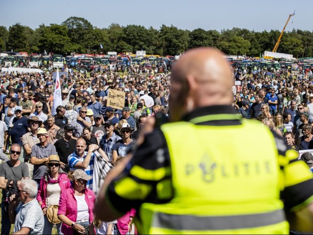 A dutch police officer (C) speaks during a farmers' protest in Stroe, on June 22, 2022. - Thousands of farmers on tractors gathered in central Netherlands on June 22, 2022, to protest the government's far-reaching plans to cut nitrogen emissions, which could see livestock reduced by almost a third. - …