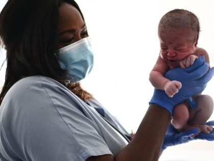 A nurse holds a new-born baby moments after her birth at the maternity ward of a hospital