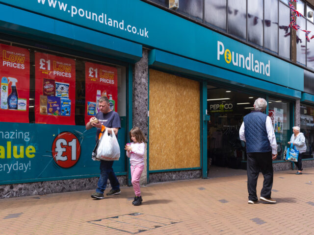 Members of the public pass by a neglected branch of Poundland, a chain of value shops wher